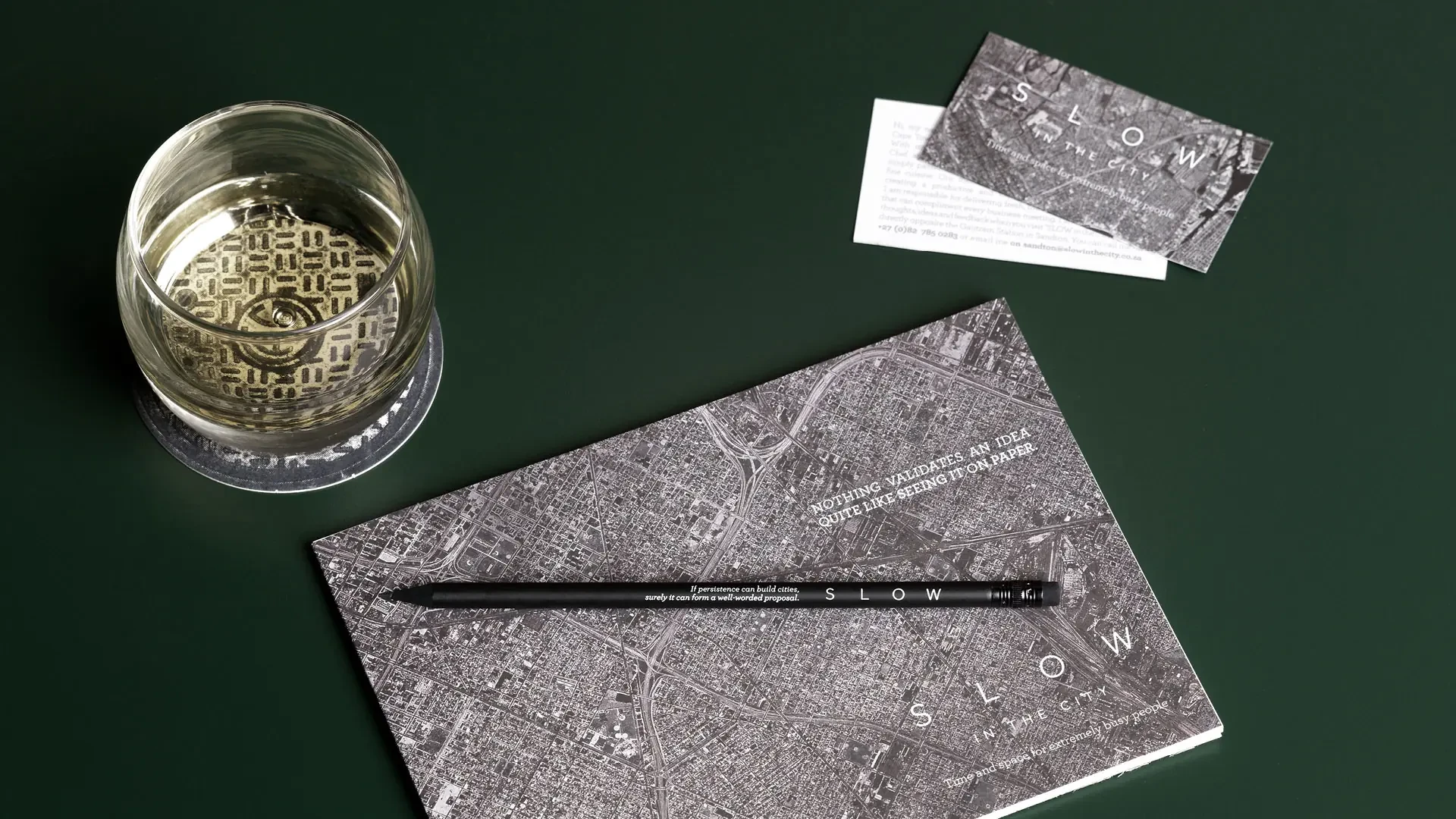 SLOW in the City printed map card, business card, pencil and etched glass on a green surface