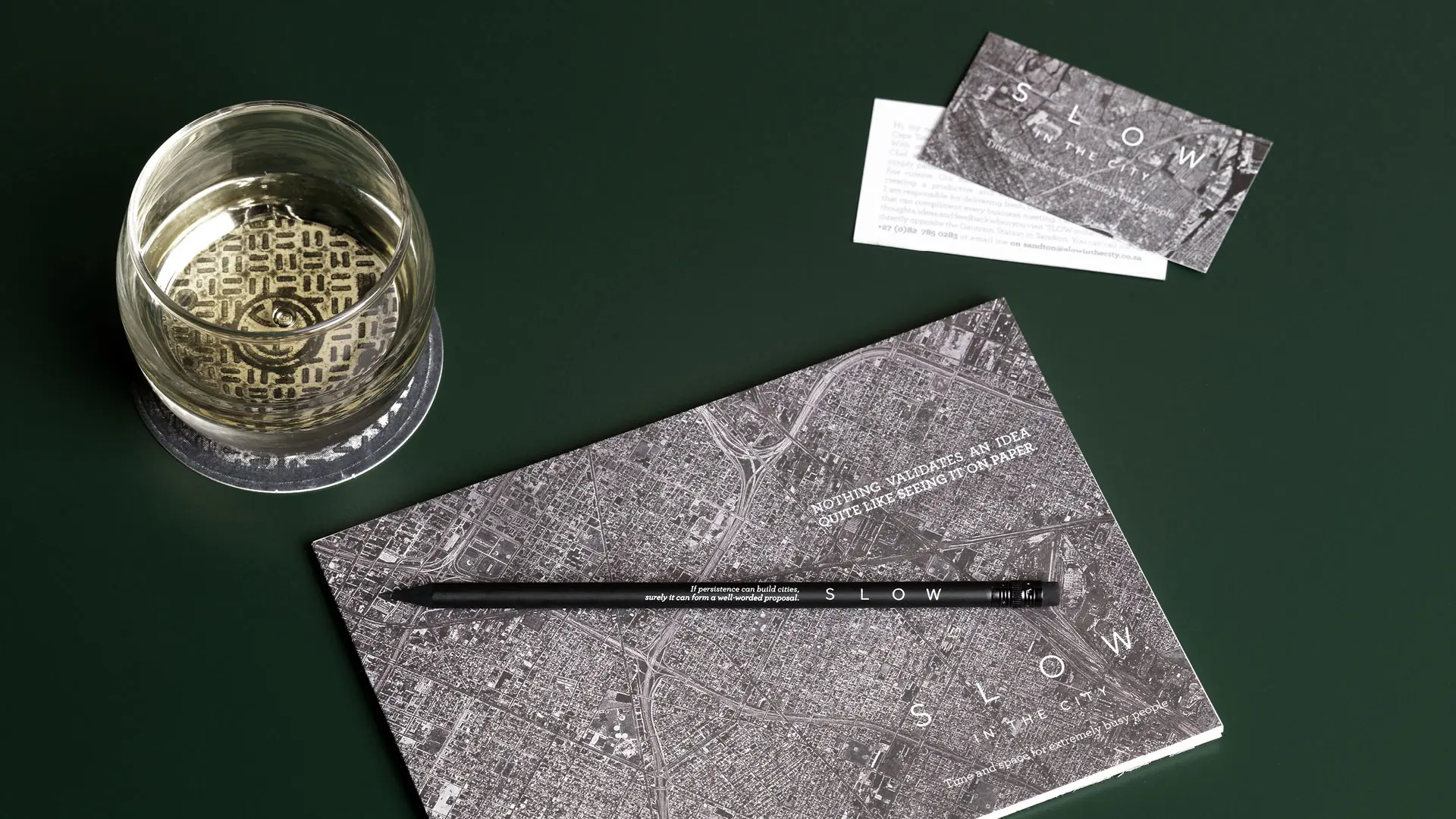 SLOW in the City printed map card, business card, pencil and etched glass on a green surface